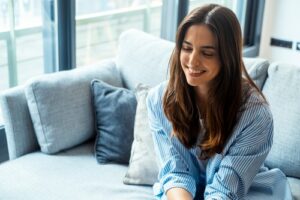 Young woman smiles while listening to her unseen psychotherapist.
