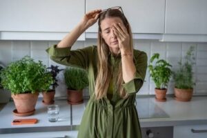 Woman rubbing her eyes feeling stress, considering therapy.